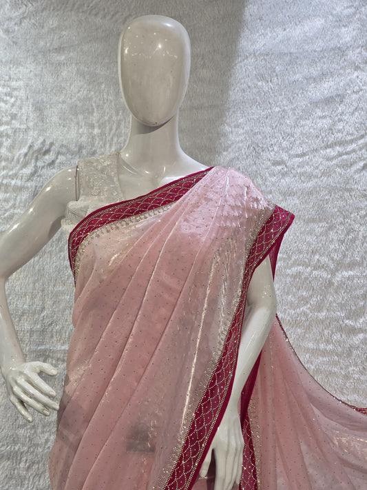 A luxurious baby pink pure satin silk saree adorned with delicate overall small stone work that gives a subtle festive sparkle. The saree is elevated with a contrast dark pink border, embellished with matching stone handwork, adding richness and definition to the drape. Paired with a dark pink contrast blouse, this saree is perfect for weddings, receptions, and special gatherings where timeless elegance is desired.