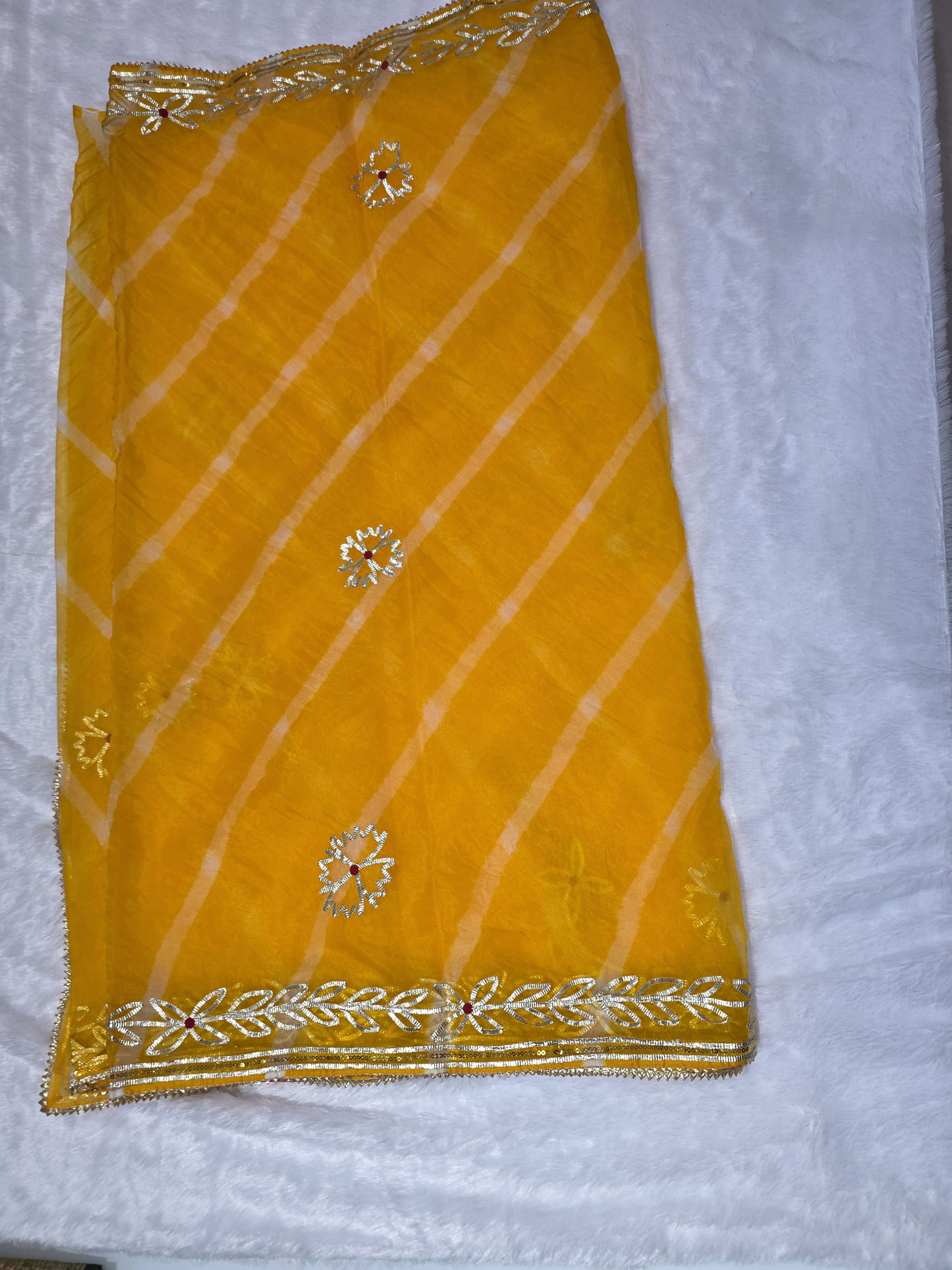 A bright and cheerful organza saree styled with leheriya pattern and gold gota patti border. Festive, light and elegant — great for haldi ceremonies. Teamed with a self blouse for a complete look.