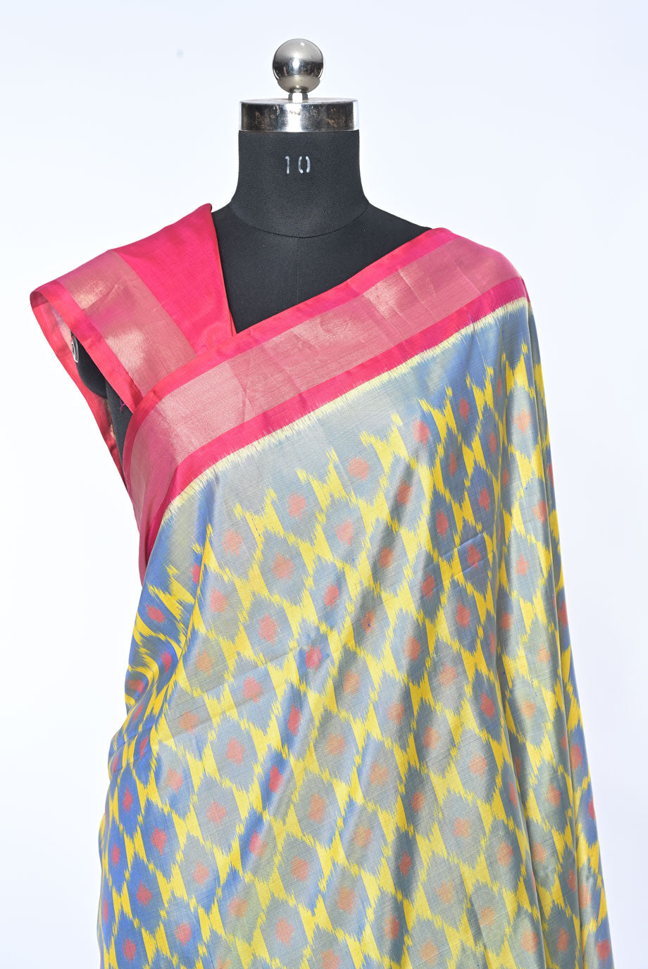 Saree with a pink border and multicolored pattern on a mannequin against a white background