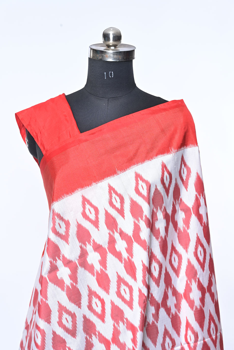 Red and white patterned fabric draped over a mannequin on a white background