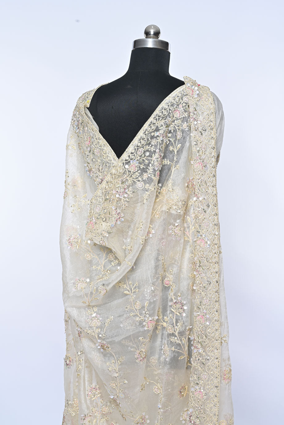 Beige saree with floral patterns on a mannequin against a light gray background Fabric off white organza saree for weddings and festive occasions
