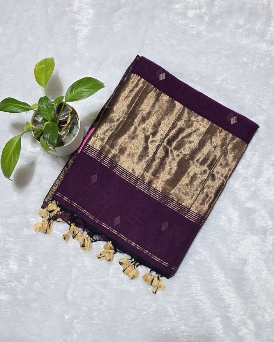 Woman wearing a purple saree with gold border indoors