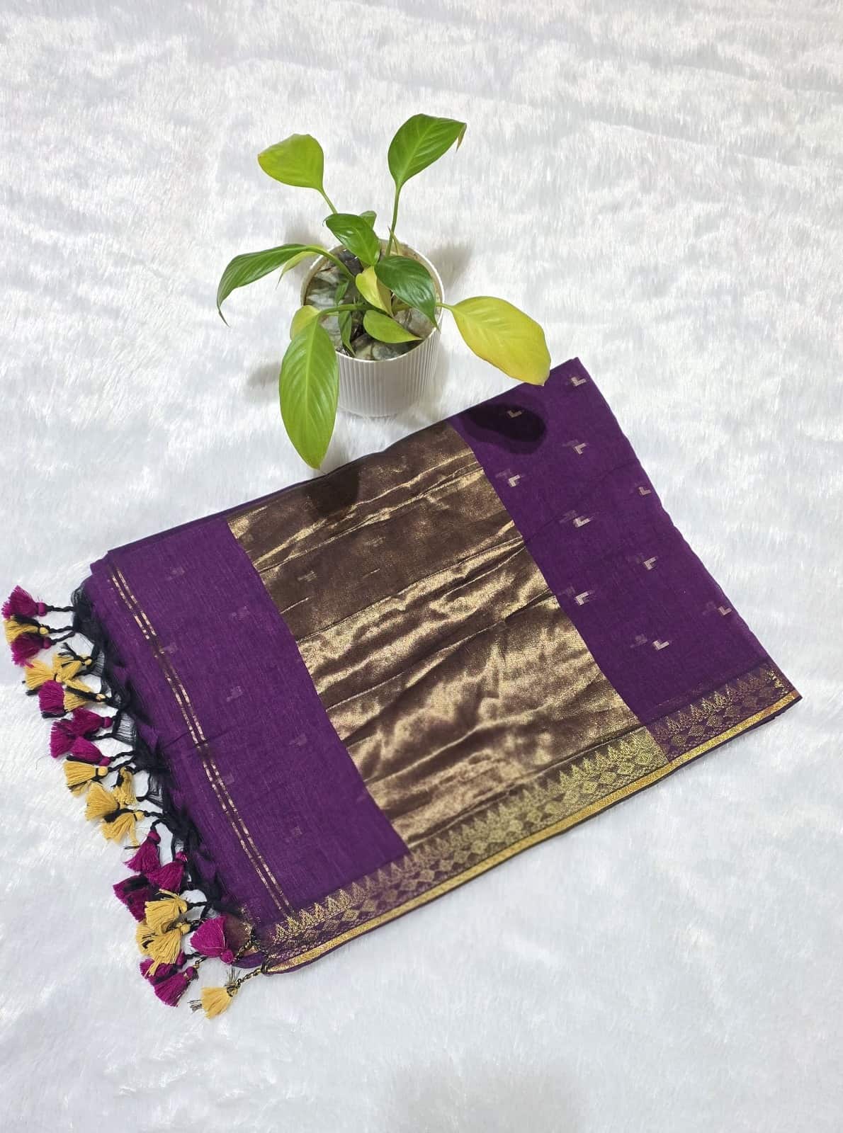 Purple and gold traditional fabric with tassels on a white background