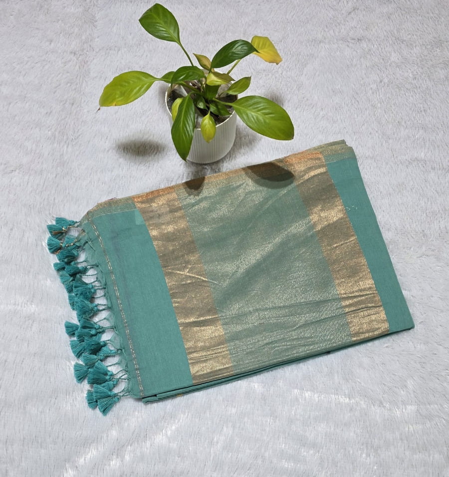 Teal green cotton saree with overall colourful triangle butties, copper zari pallu highlights and subtle golden border with tassels