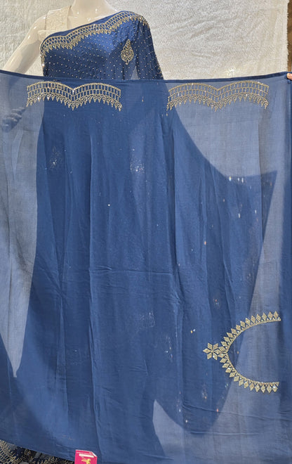 A stunning royal blue pure satin silk saree featuring rich allover stone work buttis that create a glamorous shimmer across the body. The highlight of this saree is its heavy stone-work necklace border, adding a premium designer touch. This saree comes with a matching self royal blue blouse, making it an ideal pick for evening events, parties, and wedding ceremonies where bold elegance stands out.