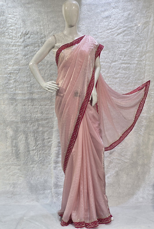 A luxurious baby pink pure satin silk saree adorned with delicate overall small stone work that gives a subtle festive sparkle. The saree is elevated with a contrast dark pink border, embellished with matching stone handwork, adding richness and definition to the drape. Paired with a dark pink contrast blouse, this saree is perfect for weddings, receptions, and special gatherings where timeless elegance is desired.