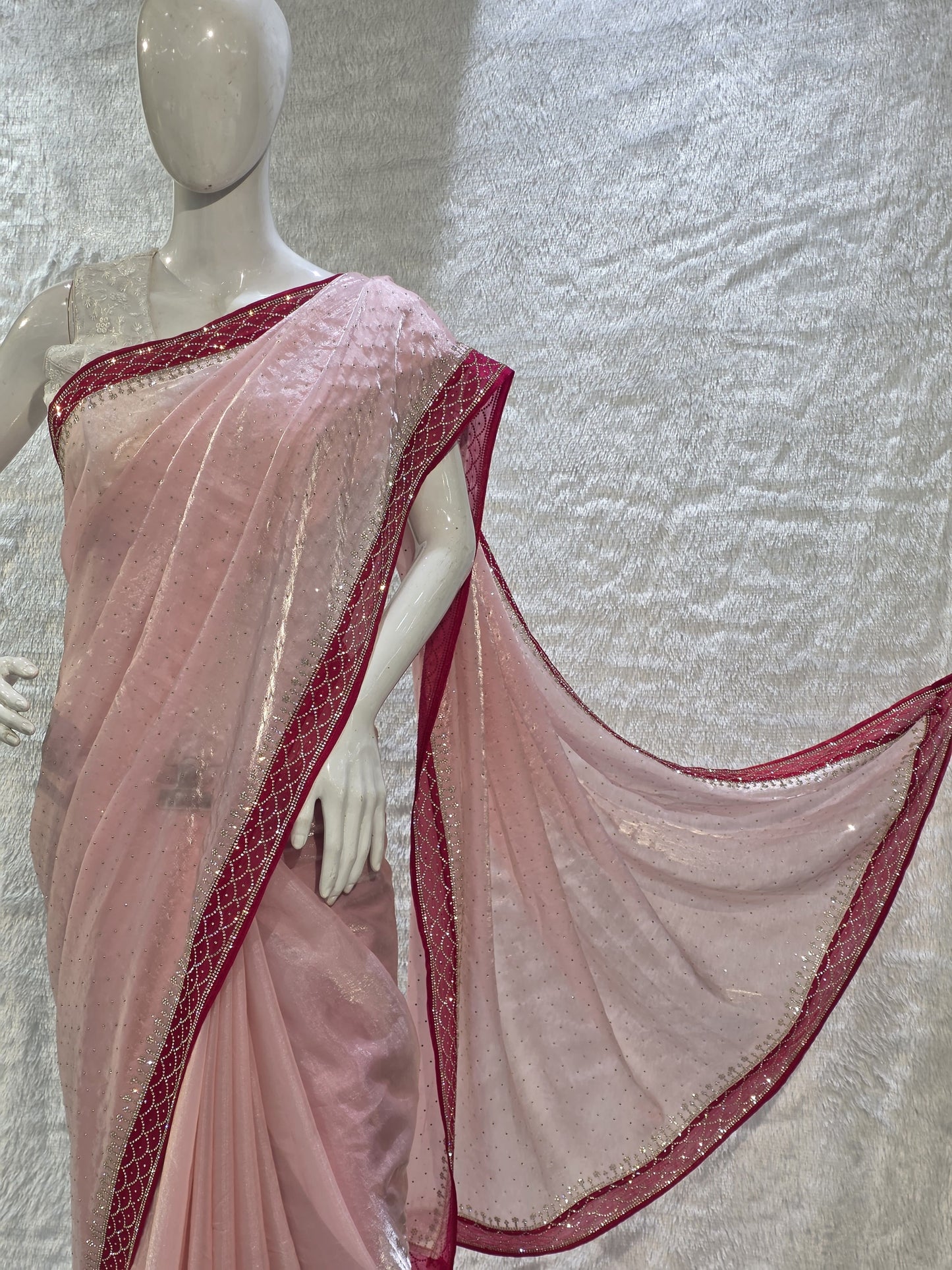 A luxurious baby pink pure satin silk saree adorned with delicate overall small stone work that gives a subtle festive sparkle. The saree is elevated with a contrast dark pink border, embellished with matching stone handwork, adding richness and definition to the drape. Paired with a dark pink contrast blouse, this saree is perfect for weddings, receptions, and special gatherings where timeless elegance is desired.