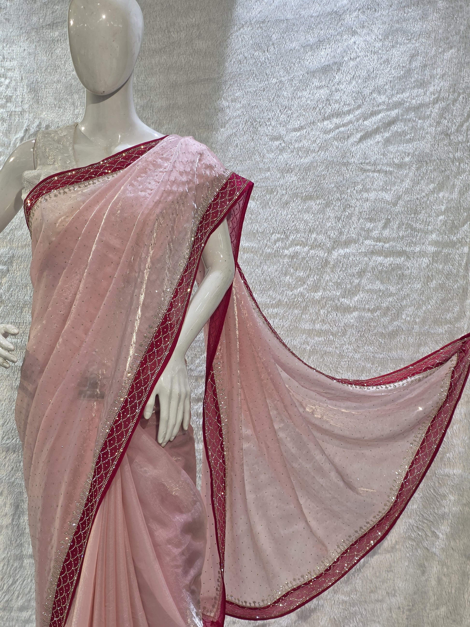 A luxurious baby pink pure satin silk saree adorned with delicate overall small stone work that gives a subtle festive sparkle. The saree is elevated with a contrast dark pink border, embellished with matching stone handwork, adding richness and definition to the drape. Paired with a dark pink contrast blouse, this saree is perfect for weddings, receptions, and special gatherings where timeless elegance is desired.