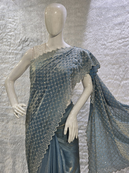 A vibrant sky blue pure satin silk saree embellished with sharp heavy stone work across the body, giving it a bright and festive shine. The saree comes with a running sky blue blouse for a seamless monochrome designer look. Its subtle elegance and rich shine make it perfect for festive events, haldi functions, and celebrations.