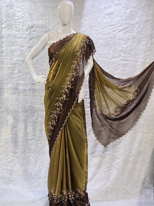 This premium copper pure satin silk saree features a stylish plain body complemented by a beautifully crafted border with floral stone work and tikali detailing. The added necklace border design enhances its regal appeal. Paired with a contrast chocolate-brown blouse, this saree carries a sophisticated modern-traditional blend, perfect for festive occasions and elegant evening wear.