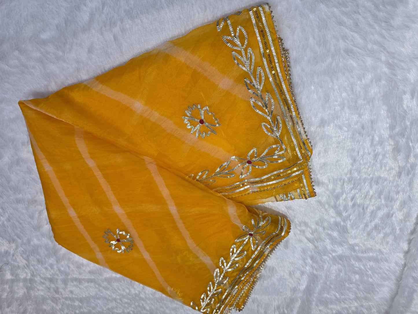 A bright and cheerful organza saree styled with leheriya pattern and gold gota patti border. Festive, light and elegant — great for haldi ceremonies. Teamed with a self blouse for a complete look.