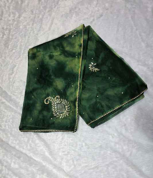 A  organza saree beautifully embellished with traditional gota patti handwork, giving it a rich festive appeal. The delicate gota motifs are arranged gracefully across the saree, enhancing its ethnic charm. Finished with a matching fine gota border for a polished traditional look. Comes with a coordinated self blouse for a complete ensemble.