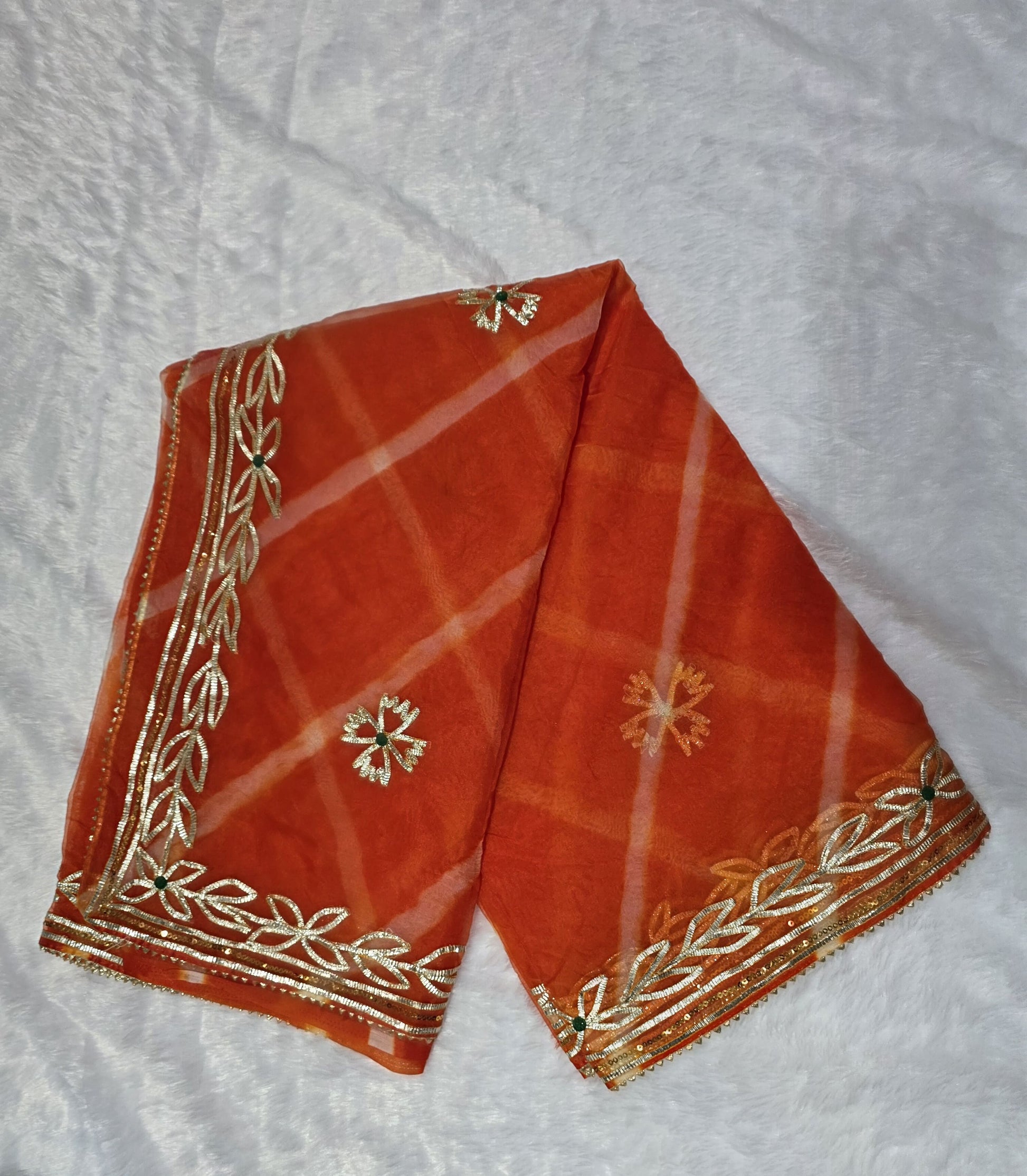 A vibrant organza saree featuring a classic leheriya pattern and rich gold gota patti border. Lightweight, festive and eye-catching — perfect for haldi, mehendi and small functions. Comes with a matching self blouse.