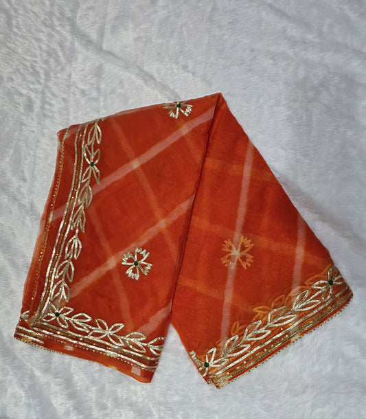 A vibrant organza saree featuring a classic leheriya pattern and rich gold gota patti border. Lightweight, festive and eye-catching — perfect for haldi, mehendi and small functions. Comes with a matching self blouse.