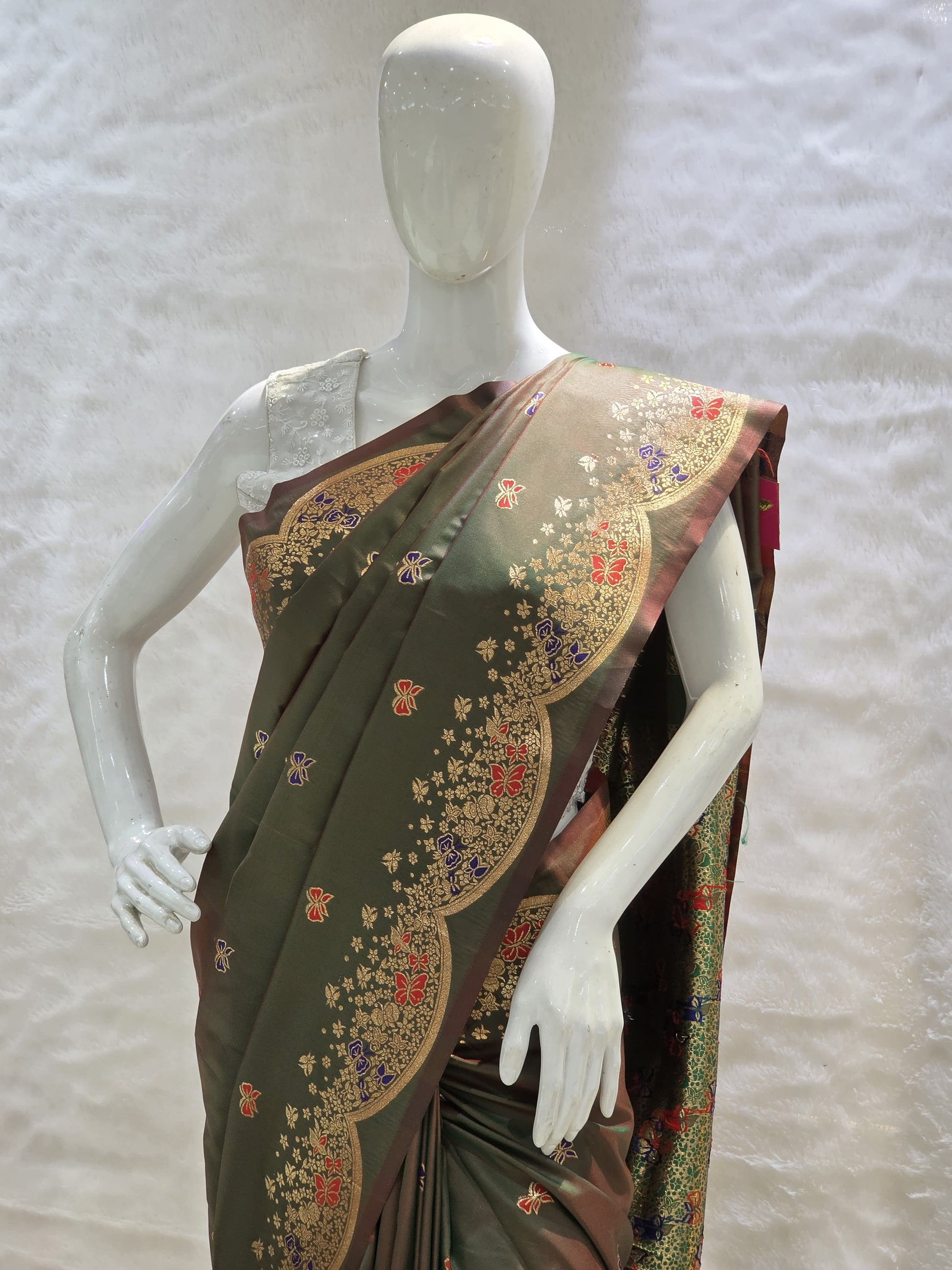 A unique tana silk paithani adorned with colorful butterfly buttis and a striking necklace-style zari border. Rich weaving adds vibrancy and festive appeal. Paired with a deep green self blouse.