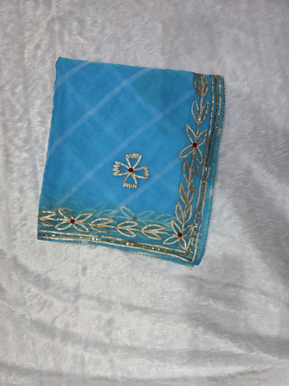 This sky-blue organza Gota pattivsaree showcases a soothing leheriya design enhanced with gold gota patti border detailing. Ideal for daytime events and celebrations. Paired with a coordinated self blouse.