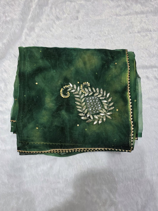 A  organza saree beautifully embellished with traditional gota patti handwork, giving it a rich festive appeal. The delicate gota motifs are arranged gracefully across the saree, enhancing its ethnic charm. Finished with a matching fine gota border for a polished traditional look. Comes with a coordinated self blouse for a complete ensemble.