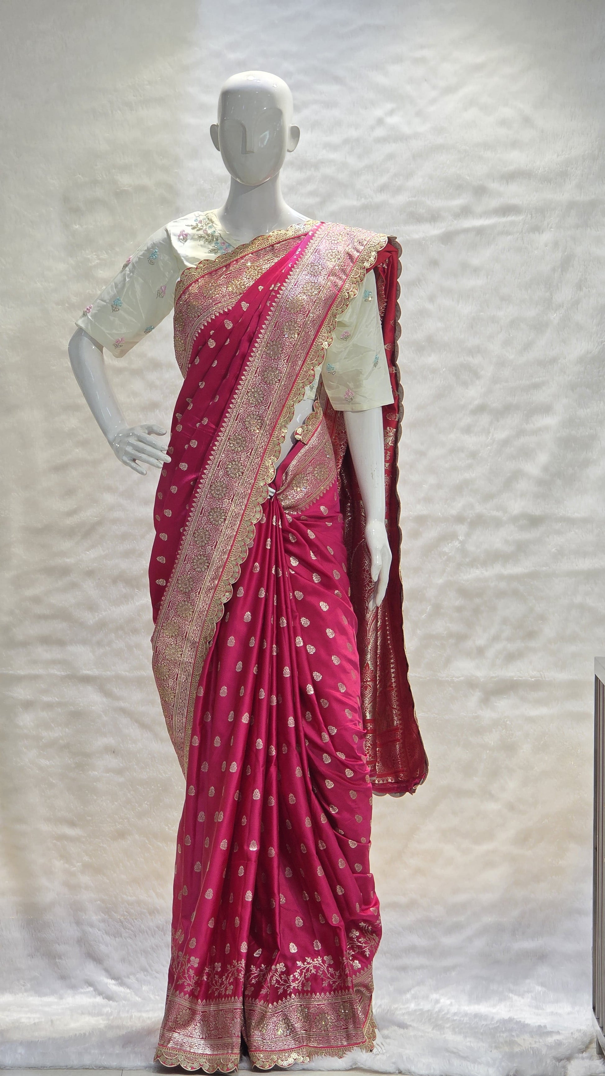 Graceful silver zari buttis all over a classic pink Banarasi base give this saree a festive sparkle with a refined cutwork border.