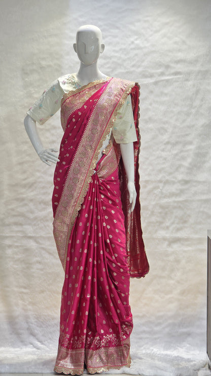 Graceful silver zari buttis all over a classic pink Banarasi base give this saree a festive sparkle with a refined cutwork border.