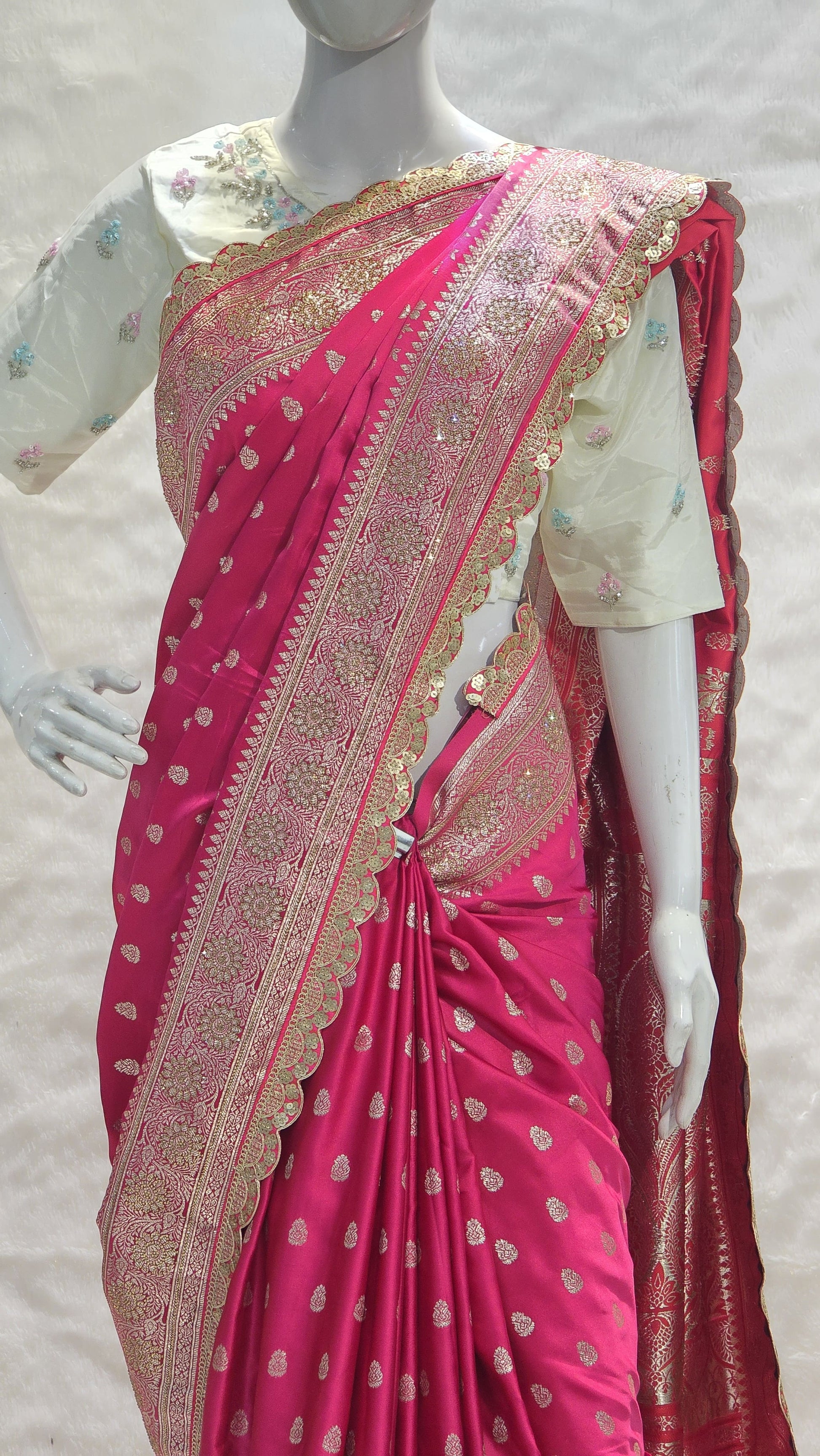 Graceful silver zari buttis all over a classic pink Banarasi base give this saree a festive sparkle with a refined cutwork border.