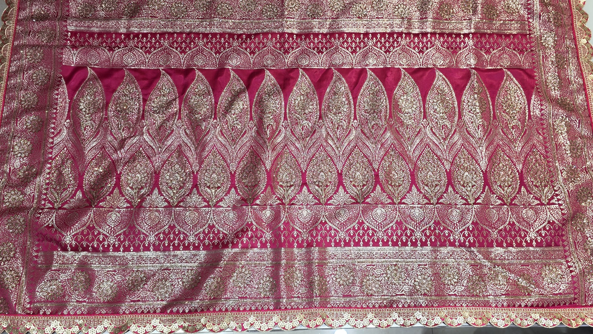 Graceful silver zari buttis all over a classic pink Banarasi base give this saree a festive sparkle with a refined cutwork border.