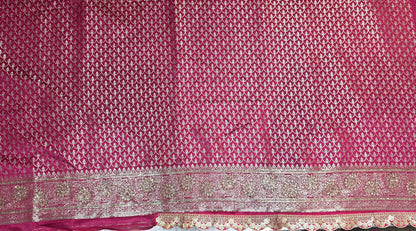 Graceful silver zari buttis all over a classic pink Banarasi base give this saree a festive sparkle with a refined cutwork border.
