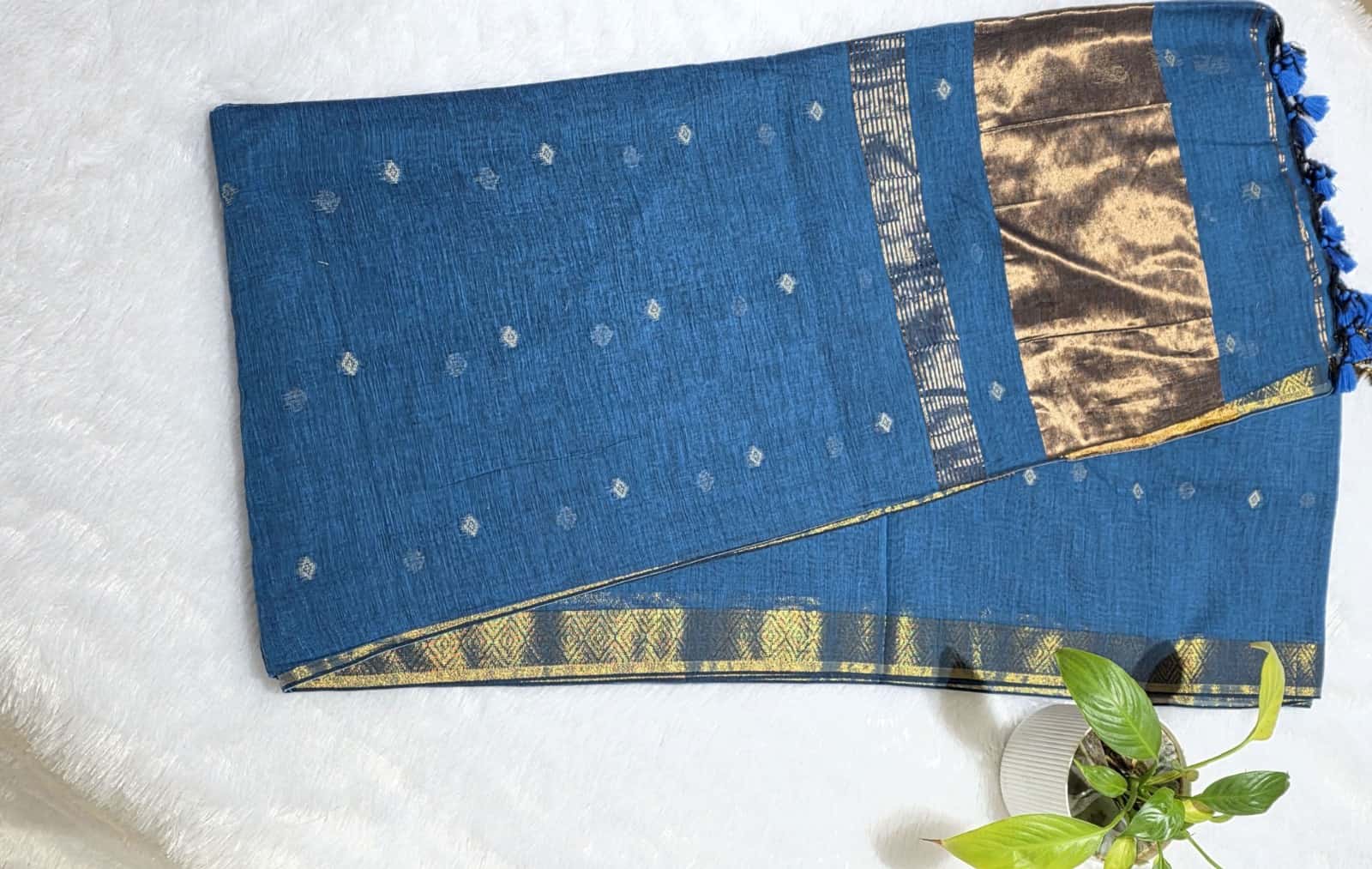 Teal blue festive cotton saree with detailed copper butti pattern, copper zari pallu, and traditional golden border.