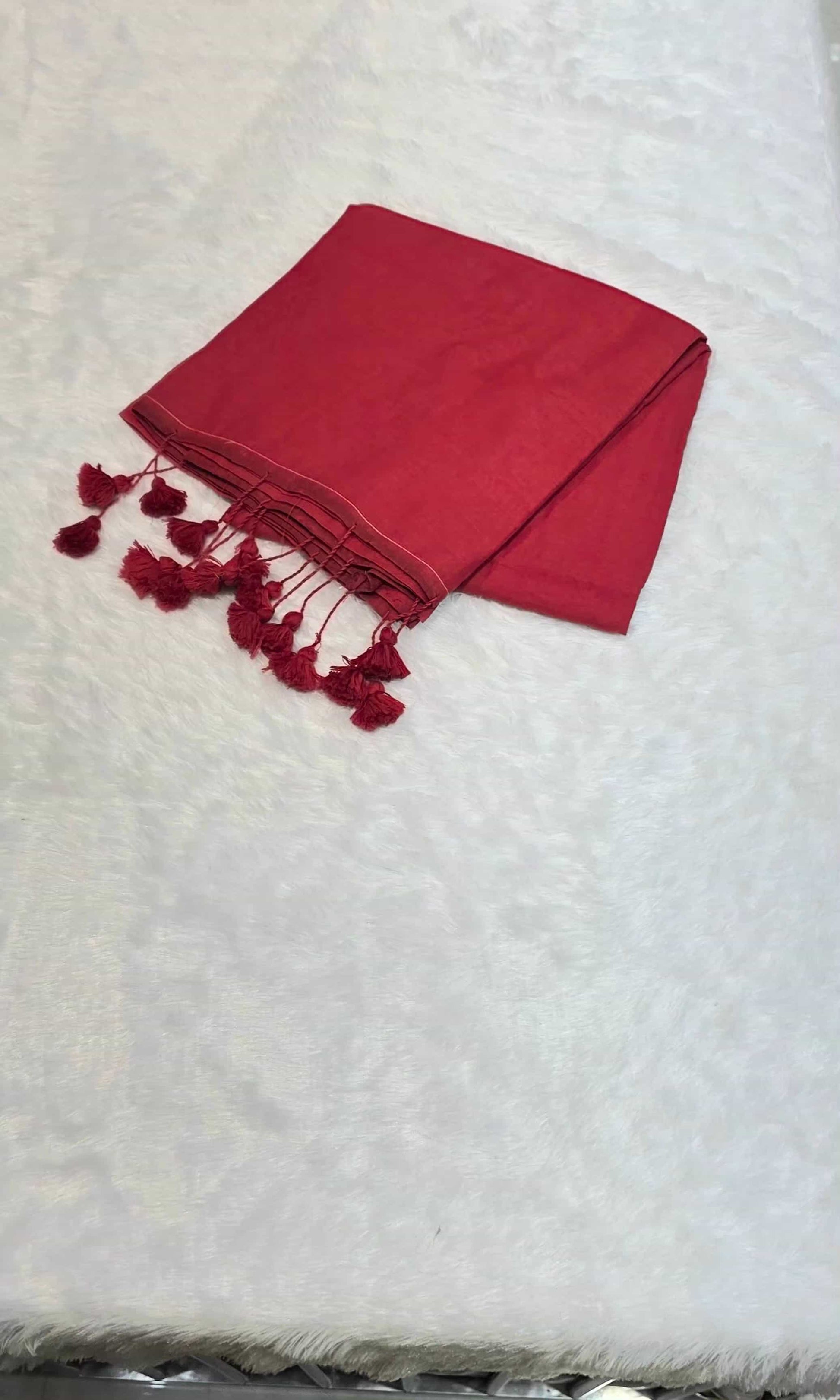 Red cotton saree with minimal border and tassels, comfortable for daily office styling.