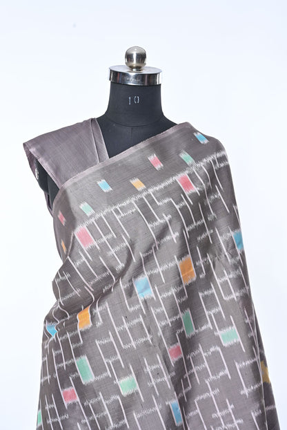 Gray saree with colorful geometric pattern on a mannequin against a white background