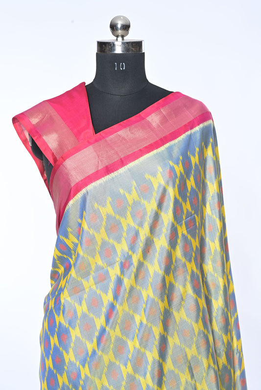 Saree with a pink border and multicolored pattern on a mannequin against a white background