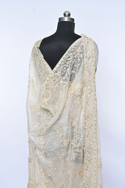Beige saree with floral patterns on a mannequin against a light gray background Fabric off white organza saree for weddings and festive occasions