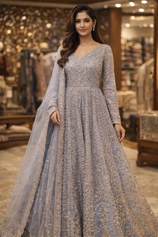  stunning powder blue front cut Anarkali crafted in delicate net fabric and adorned with intricate zari, sequin, and bead embroidery. Designed with a flattering V-neckline and a fitted bodice, the silhouette flows into a beautifully flared floor-length hem with a graceful center slit, creating a refined and regal statement. 