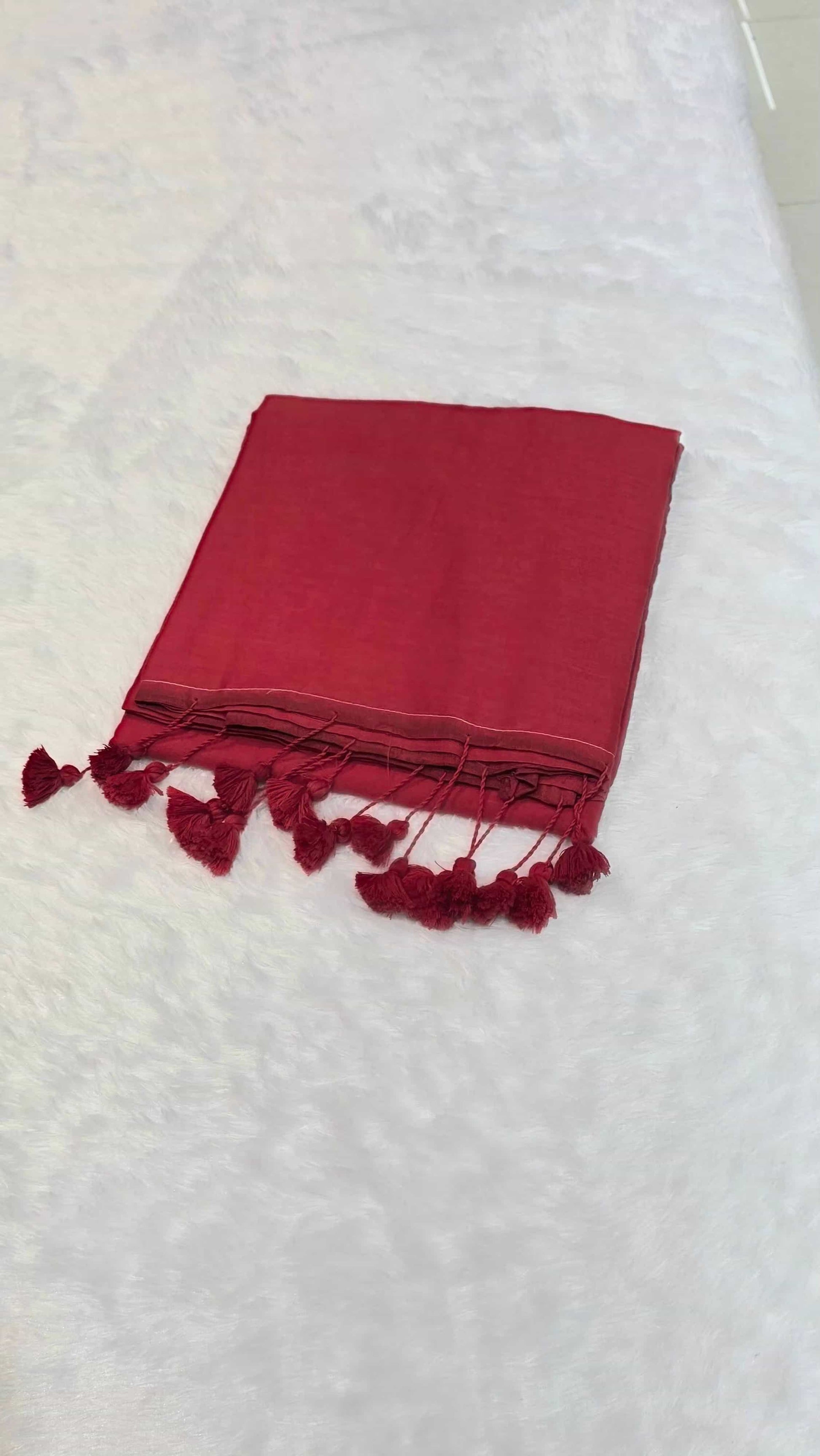 Red cotton saree with minimal border and tassels, comfortable for daily office styling.