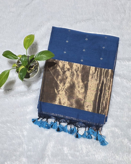 THis is stylish teal blue cotton saree with subtle butti deataling and contrast cpper zari pallu with elegant tessels at its border specially for casual outings and office wear.