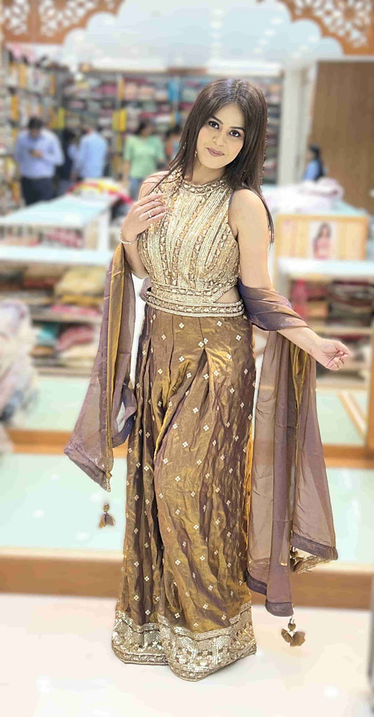 Shop the antique bronze metallic Indo-Western jumpsuit featuring heavy zardosi, sequin and mirror work, wide-leg pleated pants, and a mauve organza dupatta — perfect for sangeet, cocktail, and reception occasions.