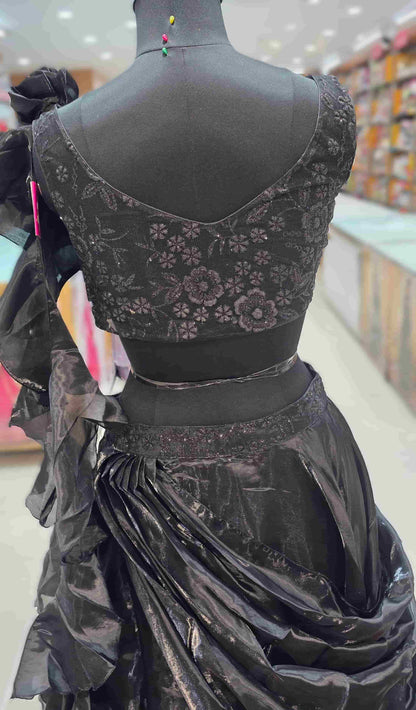 Back view of black embroidered blouse with deep V-back paired with metallic draped lehenga skirt