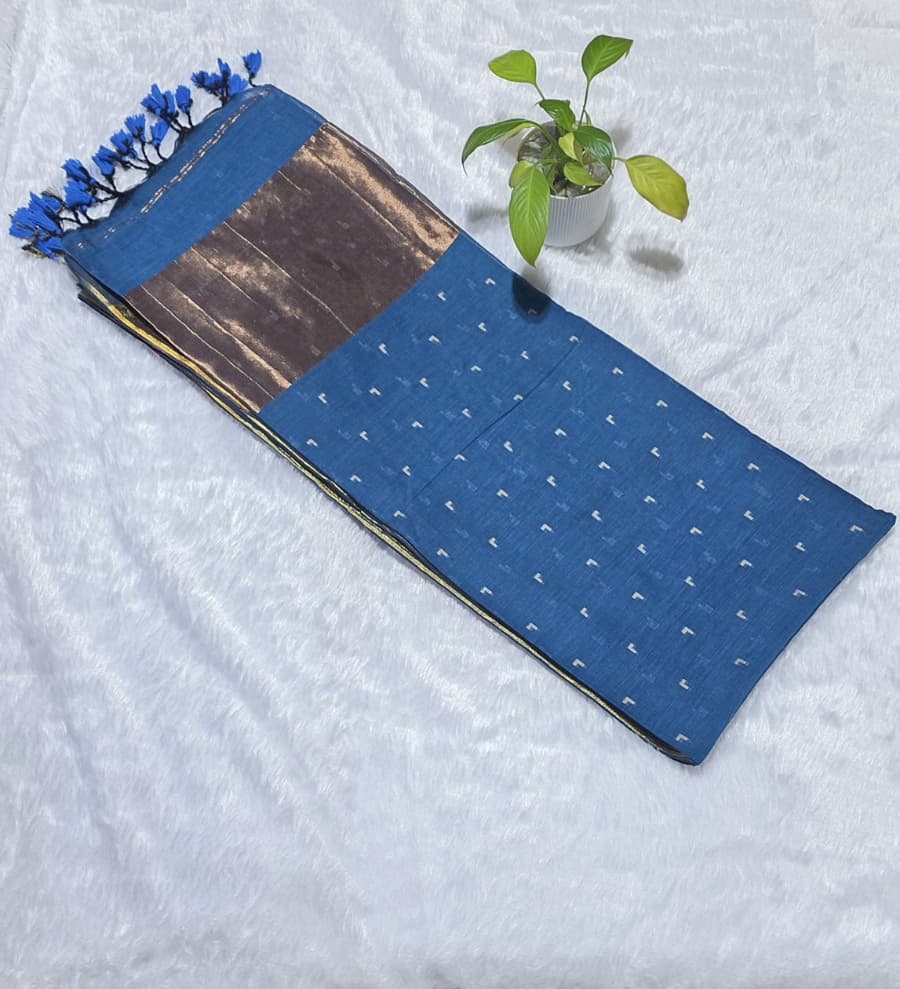 This teal blue cotton saree comes with overall small butties, minimal border, rich copper zari pallu with elegant tessels ideal for everyday use, office wear , casual wear .