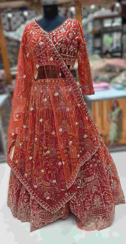 Close-up of rust orange V-neck blouse with floral sequin embroidery and sheer sleeves.