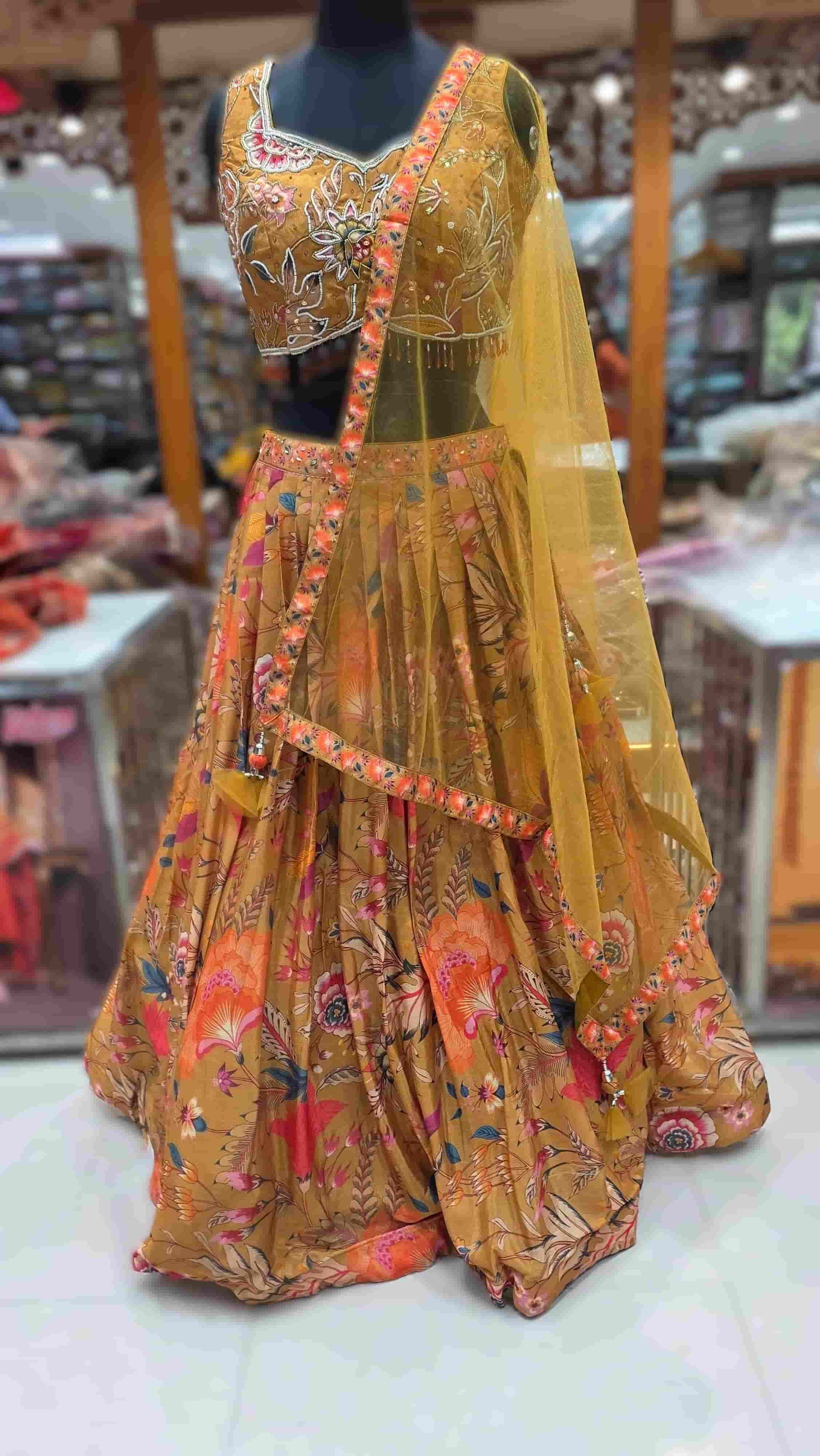 Close-up of mustard lehenga blouse with multicolour floral embroidery and bead detailing.