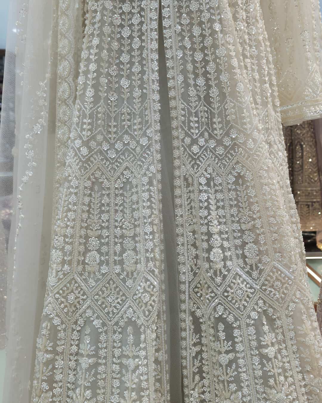 Close-up detail of ivory Anarkali gown featuring intricate pearl, sequin and bead hand embroidery on soft net fabric.