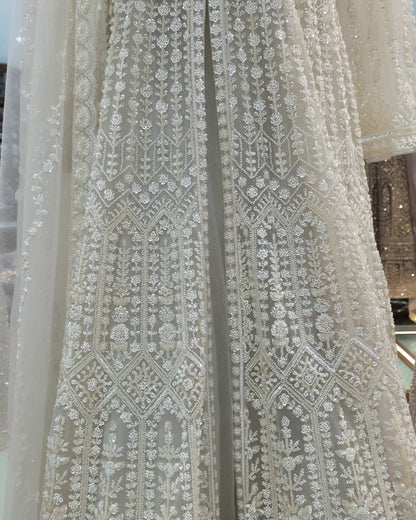 Close-up detail of ivory Anarkali gown featuring intricate pearl, sequin and bead hand embroidery on soft net fabric.