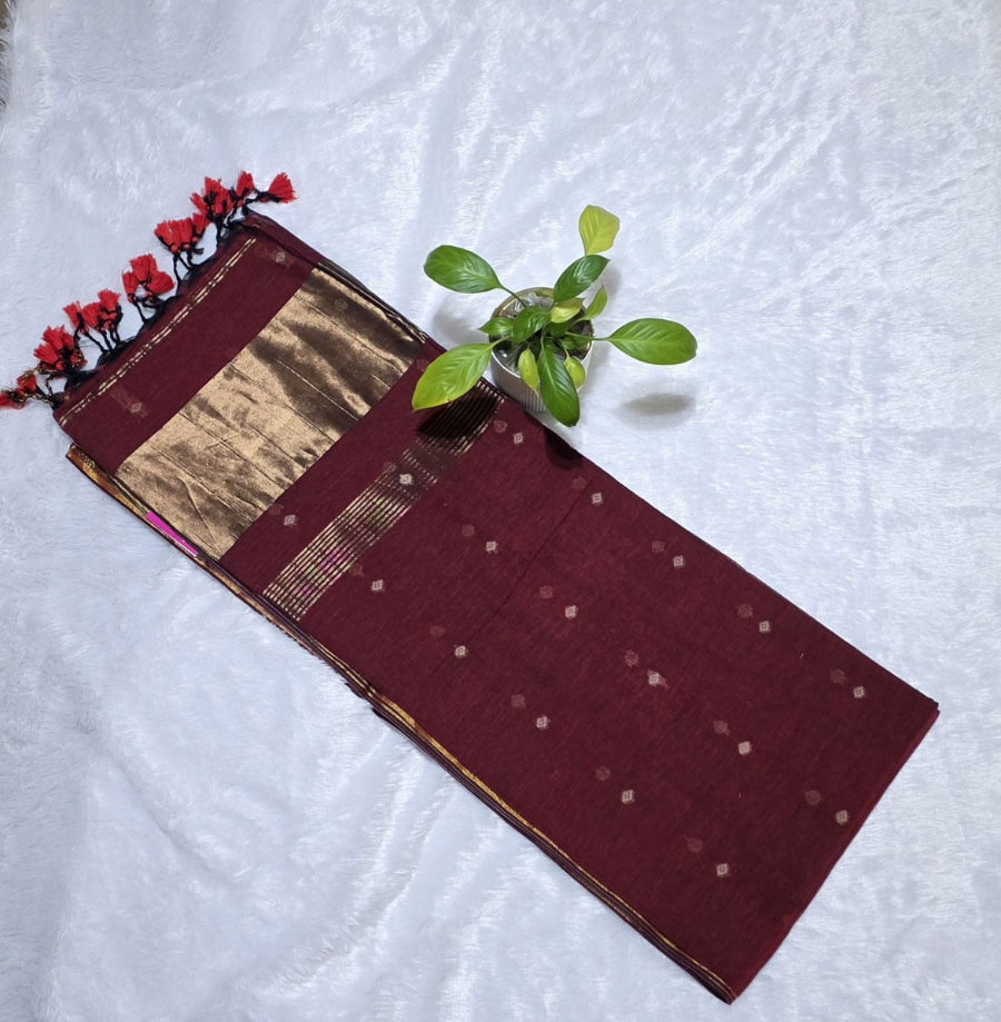 Maroon festive cotton saree adorned with copper butti pattern, zari pallu, and classic golden zari edge.