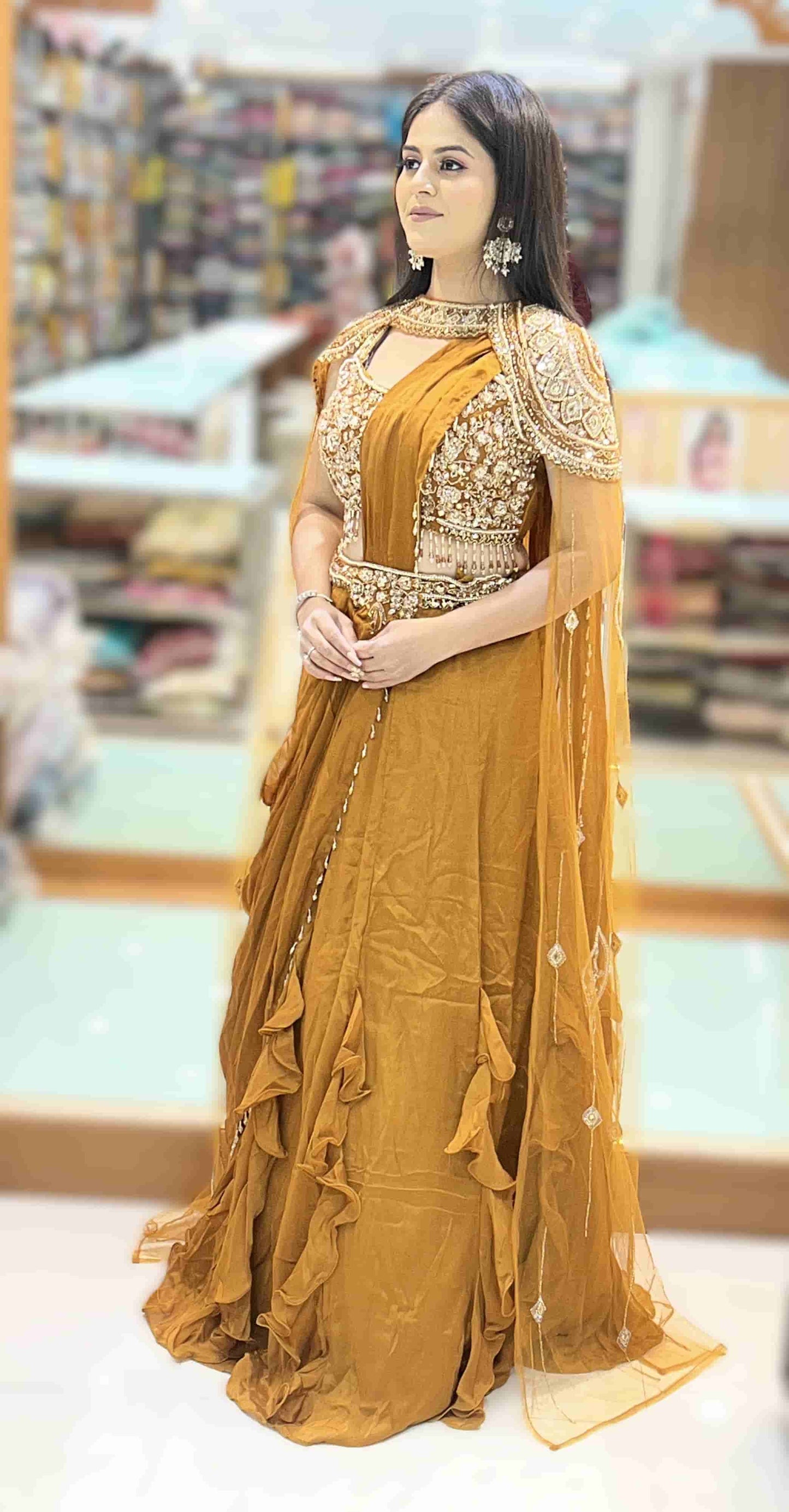 Layered ruffle hem design of mustard gold pre-draped saree highlighting flowy georgette fabric and couture silhouette.