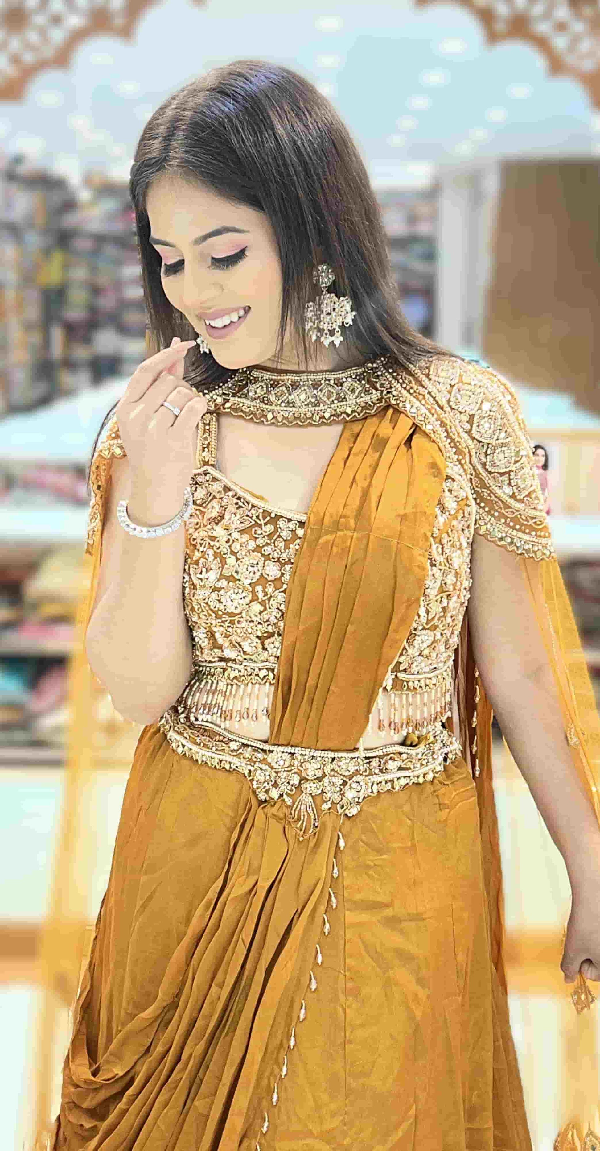 Designer mustard gold pre-draped saree with embroidered cape sleeves styled for wedding and festive occasions.