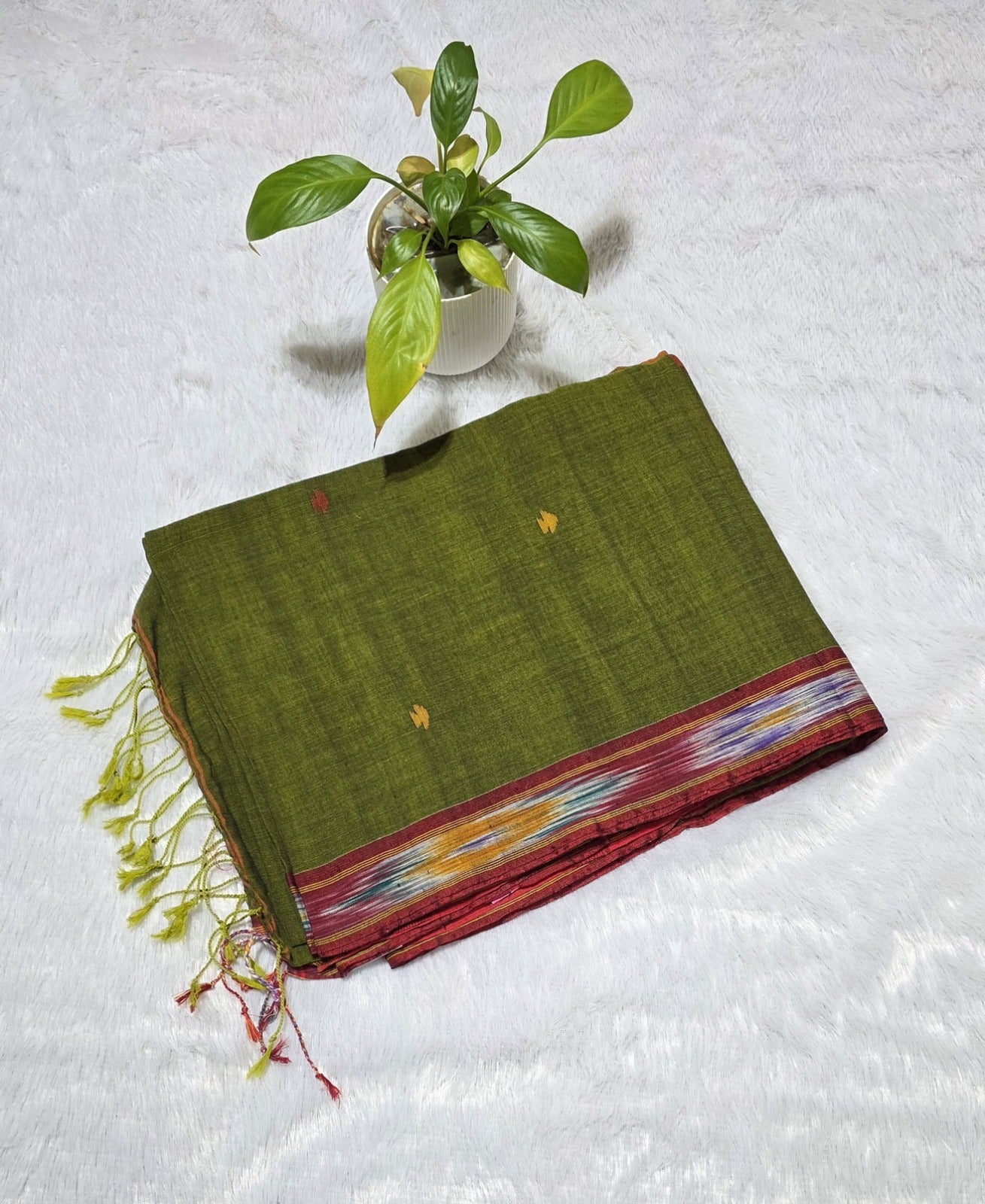 Olive green cotton saree showcasing triangle butti weaving, Ikat border pattern, contrast pallu and tassel finish. Perfect for daily wear