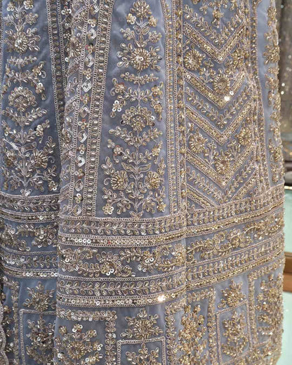 Flared hemline and front slit detail of powder blue embroidered Anarkali gown with vertical panel work.