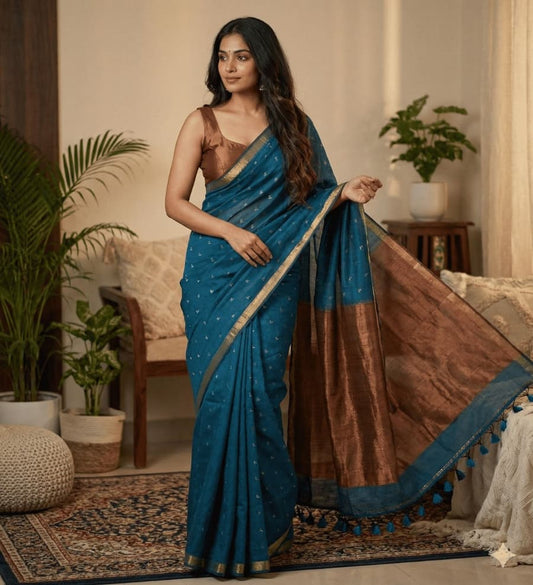 This teal blue cotton saree comes with overall small butties, minimal border, rich copper zari pallu with elegant tessels ideal for everyday use, office wear , casual wear .