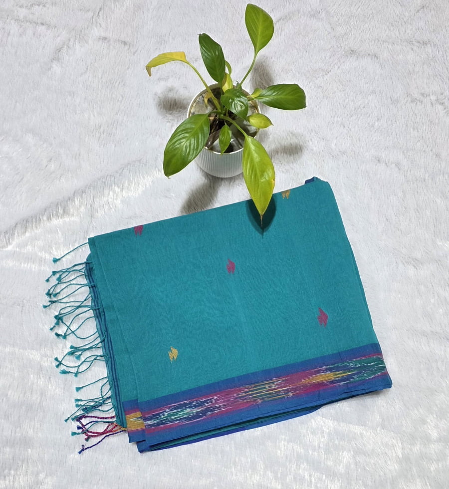 Sky blue cotton saree featuring small triangle butties, Ikat woven border, contrast pallu styling and tassel detailing. Perfect for office wear and daily wear.
