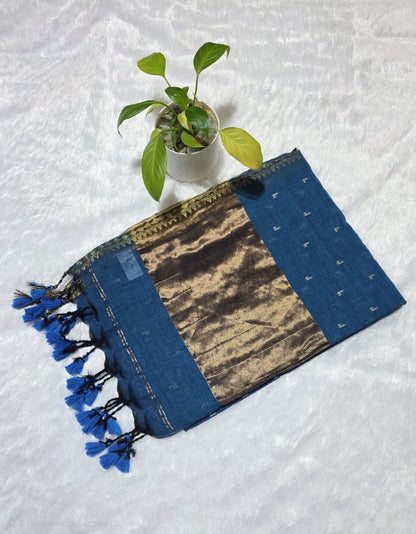 This teal blue cotton saree comes with overall small butties, minimal border, rich copper zari pallu with elegant tessels ideal for everyday use, office wear , casual wear .